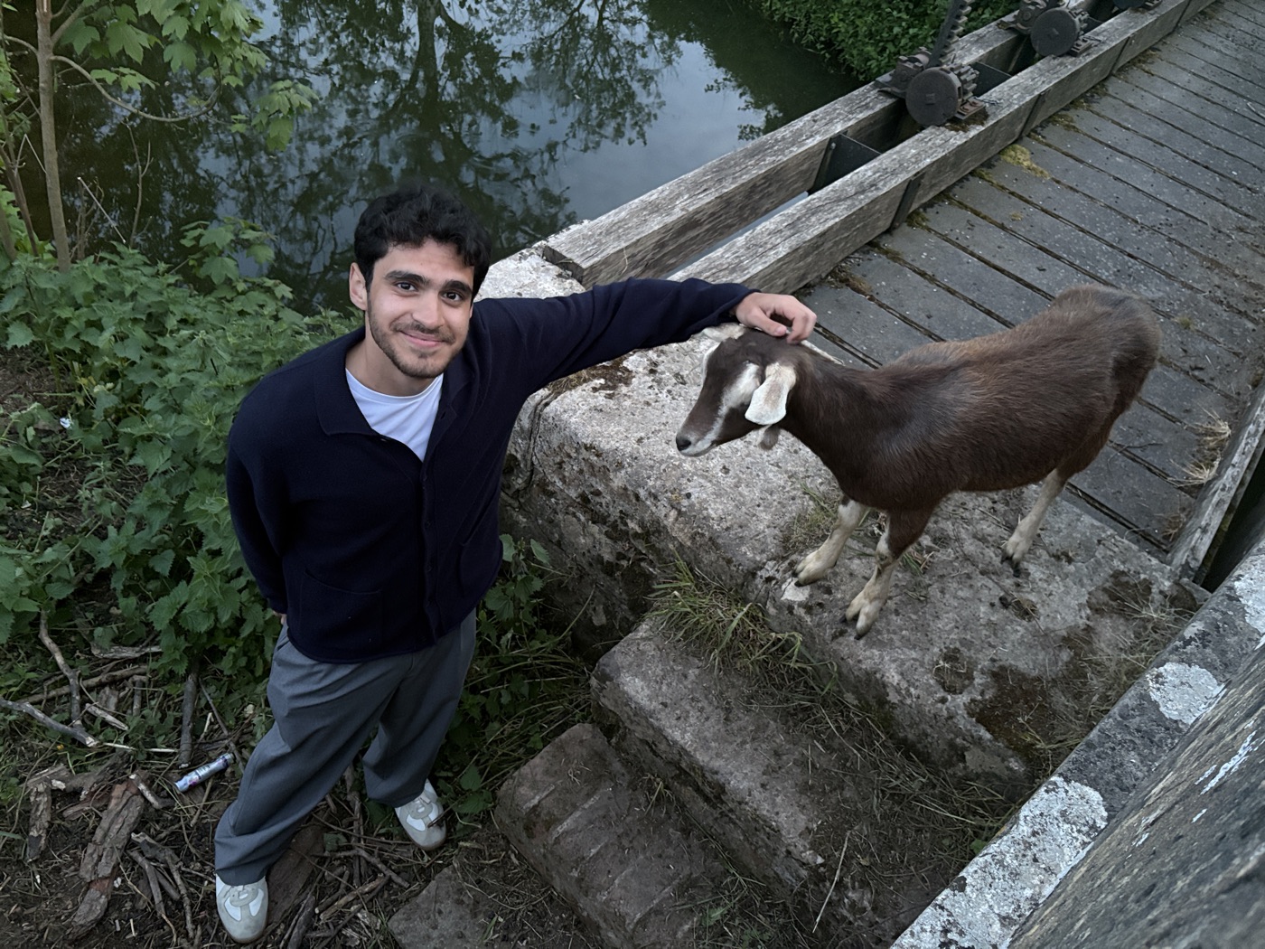 Ali by a canal, greeting a goat